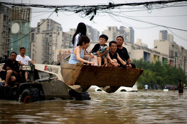 Люди едут на фронтальном погрузчике, пробираясь через паводковые воды после проливных дождей в Чжэнчжоу, провинция Хэнань, Китай - Sputnik Армения