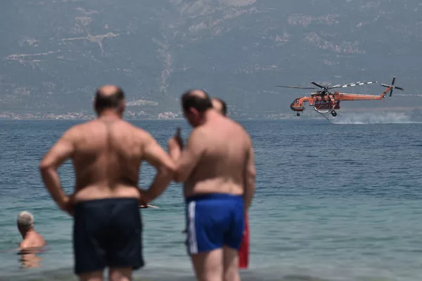 Путешественники смотрят, как вертолет Sikorsky S-64 Skycrane наполняется водой во время тушения пожара возле пляжа Ламбири в Патрах 1 августа 2021 года Путешественники смотрят, как вертолет Sikorsky S-64 Skycrane наполняется водой во время тушения пожара возле пляжа Ламбири в Патрах 1 августа 2021 года - Sputnik Армения