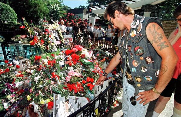 Джон Дрессен из Маастрихта смотрит на цветы и записки, оставленные доброжелателями на могиле певца Элвиса Пресли в его особняке Graceland в Мемфисе. - Sputnik Армения