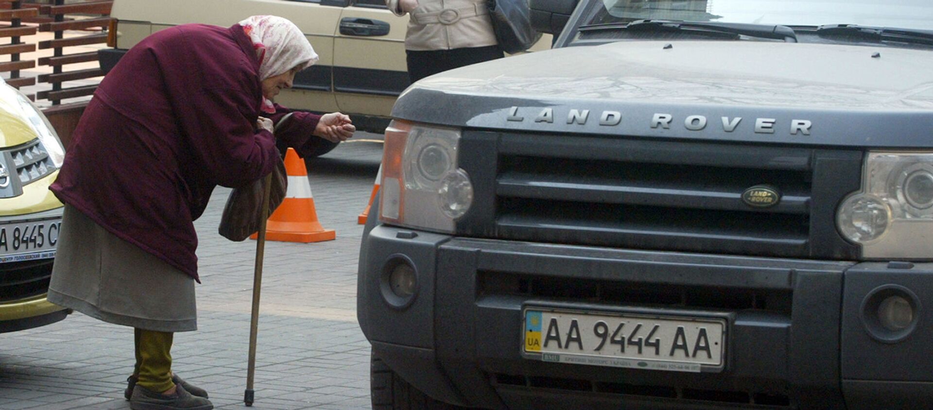 Пожилая женщина просит денег у водителей проезжающих автомобилей в центре Киева (29 марта 2007). Украина - Sputnik Արմենիա, 1920, 24.08.2021