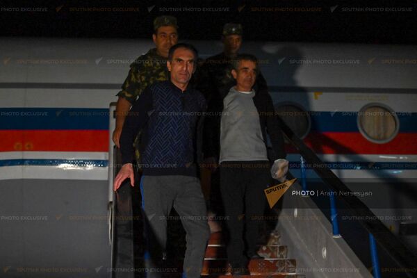 Вернувшиеся на родину военнопленные Артур Айкович Налбандян и Арамаис Грантович Торозян спускаются по трапу самолета в аэропорту Эребуни - Sputnik Армения
