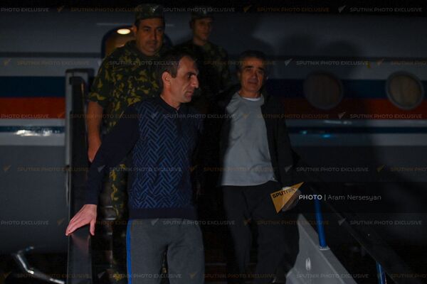 Вернувшиеся на родину военнопленные Артур Айкович Налбандян и Арамаис Грантович Торозян спускаются по трапу самолета в аэропорту Эребуни - Sputnik Армения