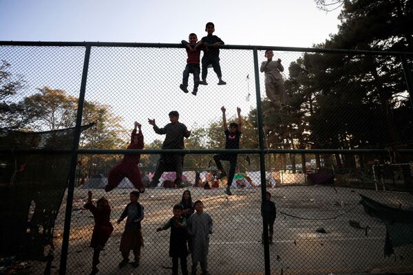 Дети из семей, бежавших из-за насилия в своей провинции, перелезают через забор в парке Шахр-э-Нау в Кабуле. - Sputnik Армения