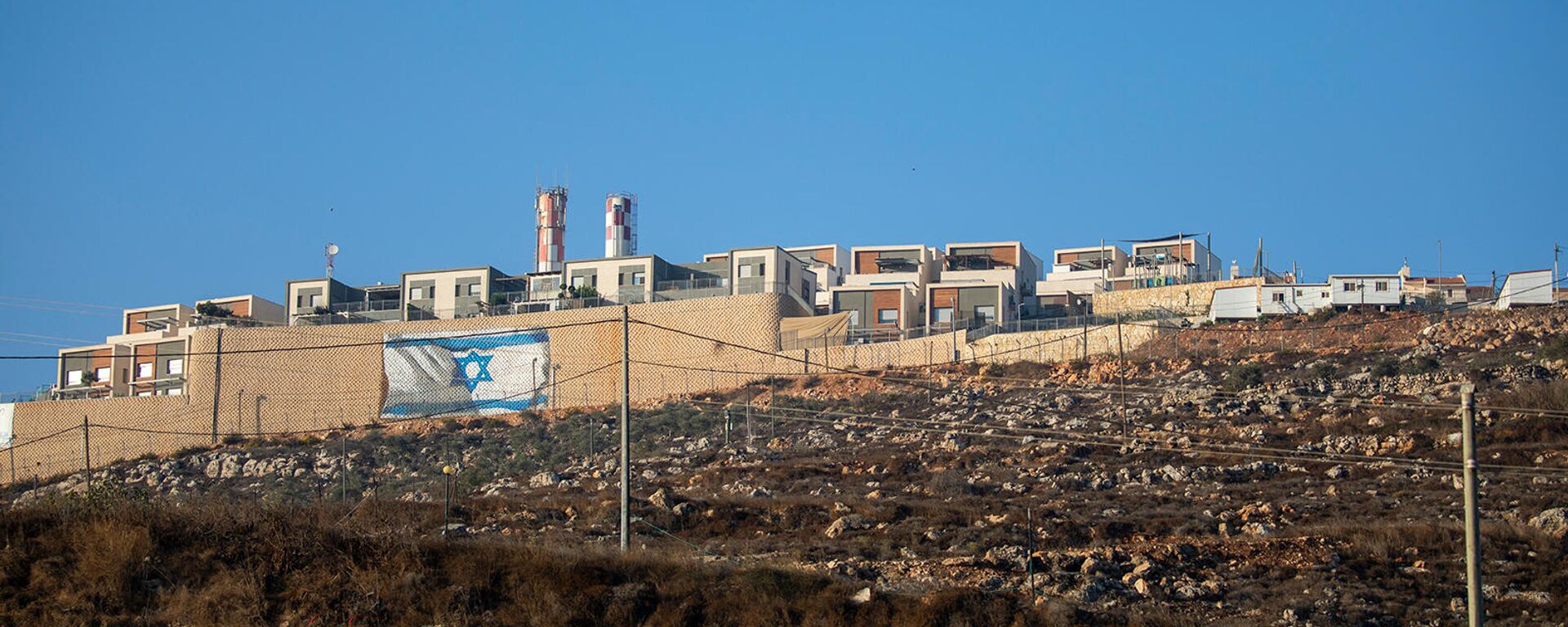 Израильский флаг на окружающей стене еврейского поселения Мигдалим на Западном берегу недалеко от палестинского города Наблус - Sputnik Армения, 1920, 18.11.2021