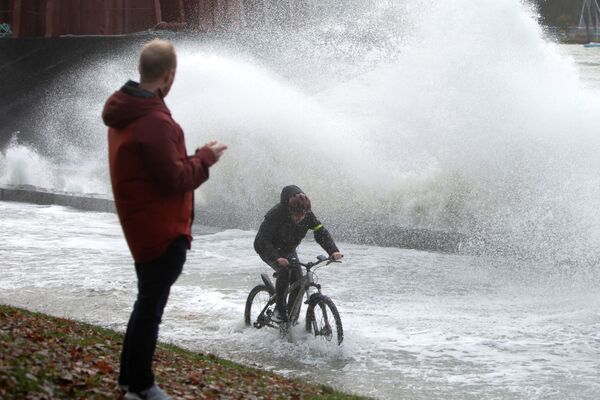 Мужчина едет на велосипеде вдоль морской стены мимо баржи, которая оторвалась от причала и разбилась о берег после того, как ливень обрушился на западную канадскую провинцию Британская Колумбия в Ванкувере 15 ноября 2021 года. - Sputnik Армения