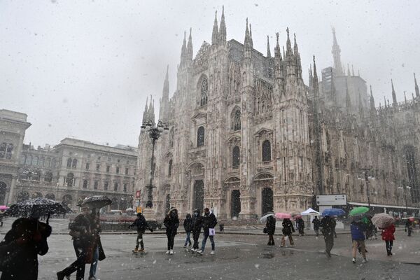 Люди идут по площади Пьяцца дель Дуомо мимо собора под снегопадом в Милане - Sputnik Армения