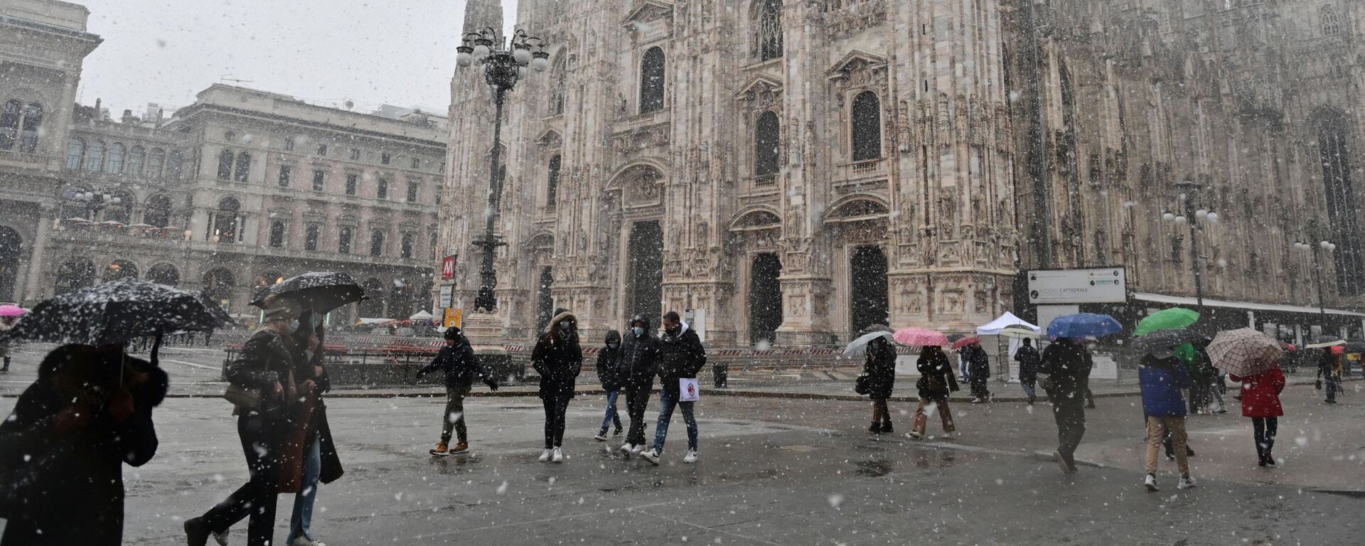 Люди идут по площади Пьяцца дель Дуомо мимо собора под снегопадом в Милане - Sputnik Армения, 1920, 11.12.2021