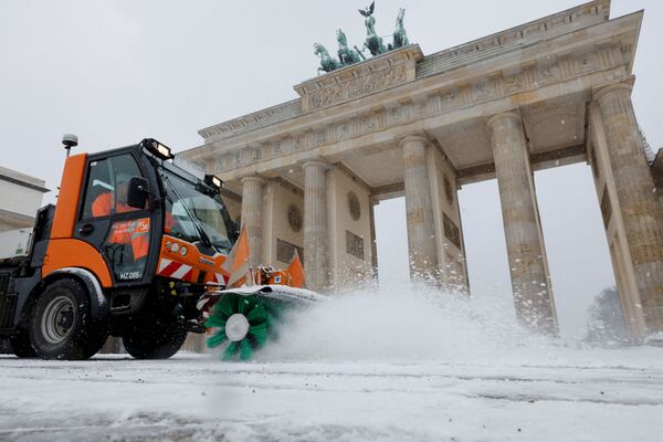 Снегоочиститель расчищает снег перед Бранденбургскими воротами во время снегопада в Берлине - Sputnik Армения