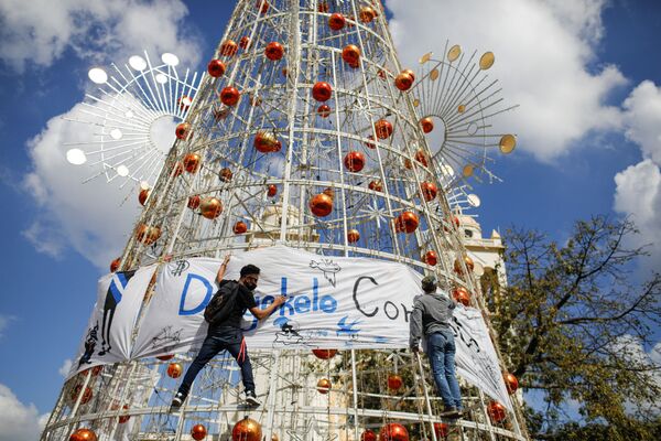 Активисты вешают баннер на елку во время акции протеста против действий правительства президента Сальвадора Найиба Букеле. - Sputnik Армения