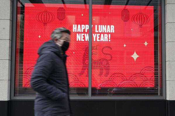 Пешеход в маске на фоне видеодисплея с поздравлением к Лунному Новому году. - Sputnik Армения