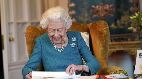 Королева Великобритании Елизавета II рассматривает фотографии памятных вещей с ее Золотого и Платинового юбилеев в Дубовой комнате в Виндзорском замке (4 февраля 2022). Англия - Sputnik Армения
