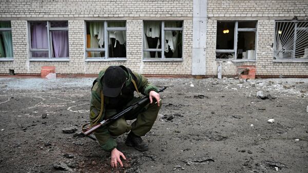 Сотрудник народной милиции ДНР возле воронки от снаряда у школы Горловки - Sputnik Армения