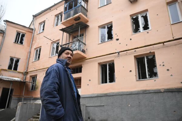 Житель у дома в Киевском районе Донецка, подвергшегося обстрелу - Sputnik Армения