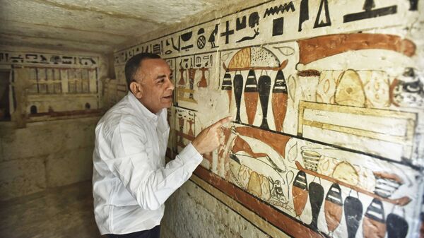 Генеральный секретарь Высшего совета древностей Мостафа Вазири рассматривает иероглифы внутри недавно обнаруженной гробницы возле знаменитой Ступенчатой пирамиды в Саккаре (19 марта 2022). Египет - Sputnik Армения