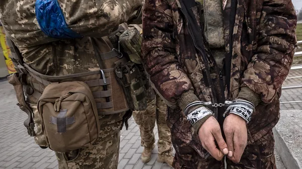Украинский военнослужащий стоит рядом с закованным в наручники российским солдатом (31 марта 2022). Харьков - Sputnik Армения