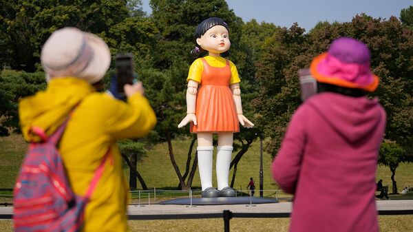 Посетители фотографируют модель куклы Янги из сериала Netflix Игра в кальмара в Олимпийском парке Сеула (26 октября 2021). Южная Корея - Sputnik Армения