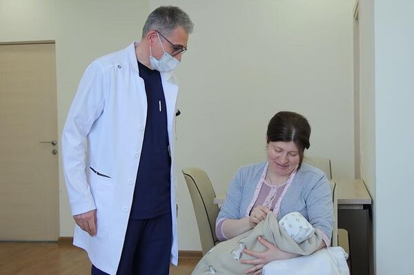 Замдиректора роддома МЦ Эребуни Давид Абовян наблюдает за новорожденным Кареном Мирзояном и его мамой Араксией Мкртумян - Sputnik Армения