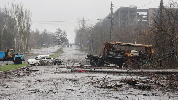 Разбитые автомобили на фоне сгоревших домов в Мариуполе (13 апреля 2022). Украина - Sputnik Армения
