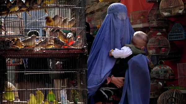 Женщина в парандже с ребенком на руках на птичьем рынке в Кабуле (8 мая 2022). Афганистан - Sputnik Армения
