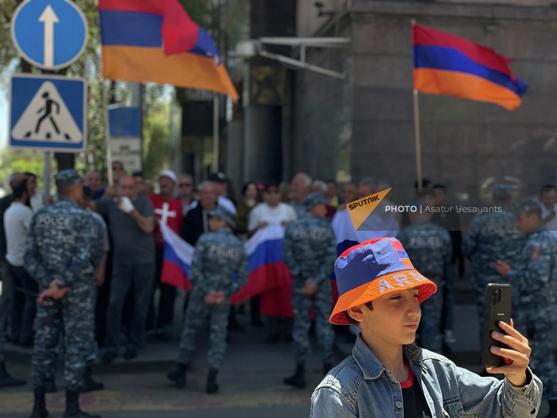 Мальчик в панаме с триколором делает селфи на фоне акции протеста у посольства России (22 мая 2022). Еревaн - Sputnik Արմենիա, 1920, 22.05.2022