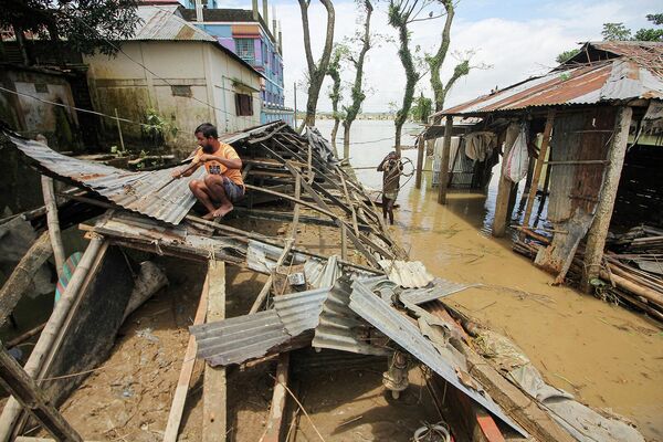 Мужчина на разрушенной крыше дома, пострадавшего от недавнего наводнения в Компанигандже, Бангладеш  - Sputnik Армения