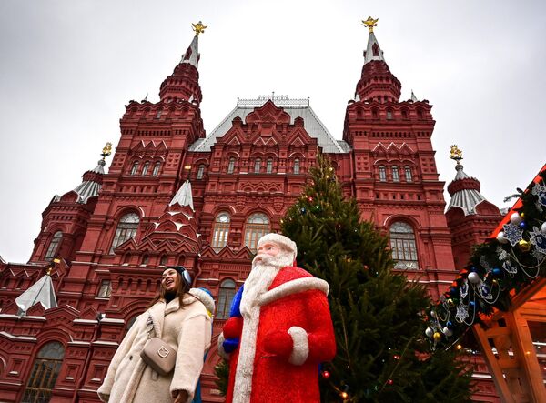 Женщина позирует фотографу рядом с фигурой Деда Мороза на Рождественской ярмарке на Красной площади у Кремля в Москве. - Sputnik Армения