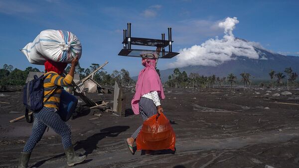 Женщины вывозят уцелевшие вещи из пострадавших от извержения вулкана Семеру домов в деревне Самбервулух, Восточная Ява (6 декабря 2022). Индонезия - Sputnik Армения