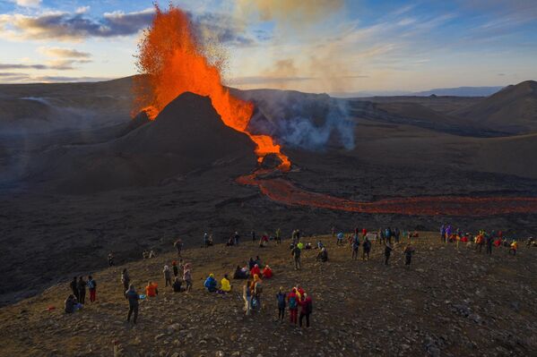 Люди наблюдают, как лава вытекает из извержения вулкана Фаградальсфьялл на полуострове Рейкьянес, Исландия. - Sputnik Армения