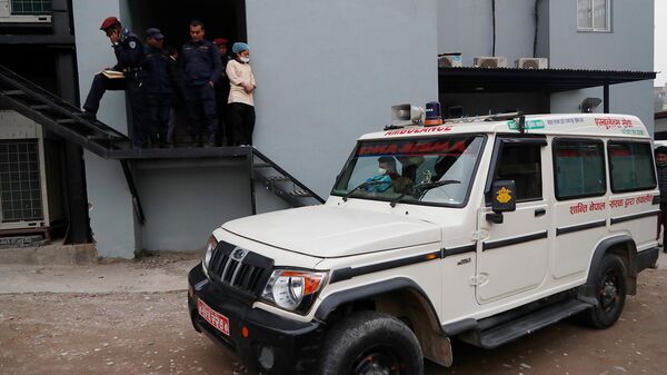 Непальский полицейский собирает информацию, пока машина скорой помощи, перевозящая тела индийских туристов, стоит у больницы в Катманду (21 января 2020). Непал - Sputnik Армения