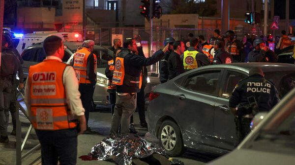 Сотрудники израильской службы экстренной помощи и сил безопасности стоят возле накрытого тела на месте предполагаемого нападения (27 января 2023). Восточный Иерусалим - Sputnik Армения