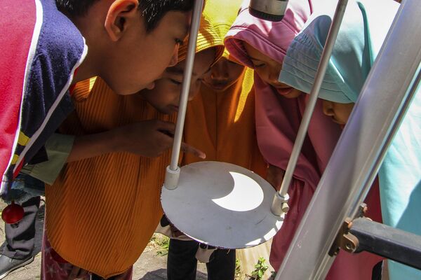 Երեխաները դիտում են Արևի խավարումը, որն արտացոլվում է Ինդոնեզիայի Ջոգյակարտա քաղաքում գտնվող աստղադիտակի հիմքում - Sputnik Արմենիա
