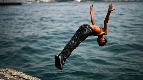 Юноша ныряет в Босфор на набережной Каракой жарким летним днем (14 июля 2023). Стамбул - Sputnik Армения