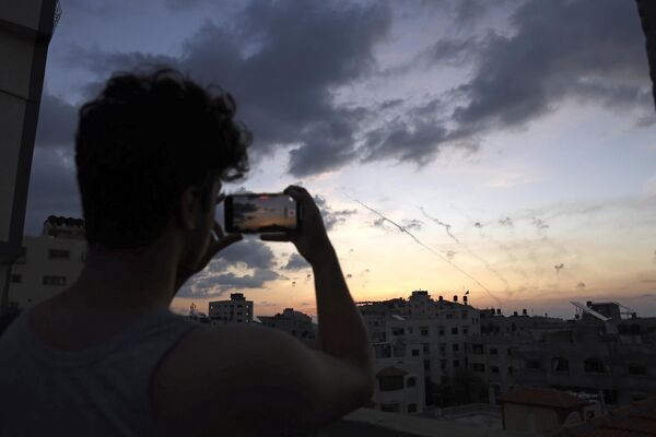 Мужчина снимает на телефон момент запуска ракет из Газы по Израилю. - Sputnik Армения