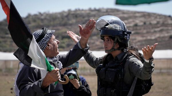 Палестинский протестующий спорит с сотрудницей израильских сил безопасности во время демонстрации против израильских поселений в деревне Карьют (15 сентября 2023). Наблус - Sputnik Армения