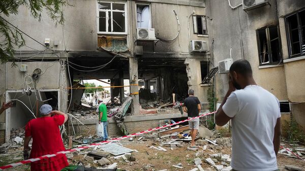 Местные жители осматривают поврежденное жилое здание после попадания в него ракеты, выпущенной из сектора Газа (9 октября 2023). Ашкелон - Sputnik Արմենիա