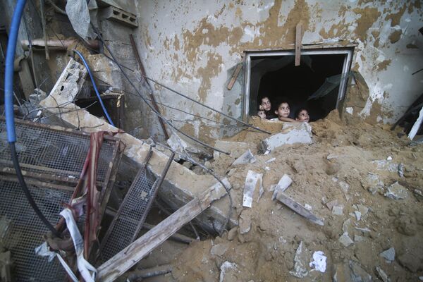 Палестинские дети выглядывают из-под руин разрушенного здания в результате израильских авиаударов в Рафахе, сектор Газа. - Sputnik Армения