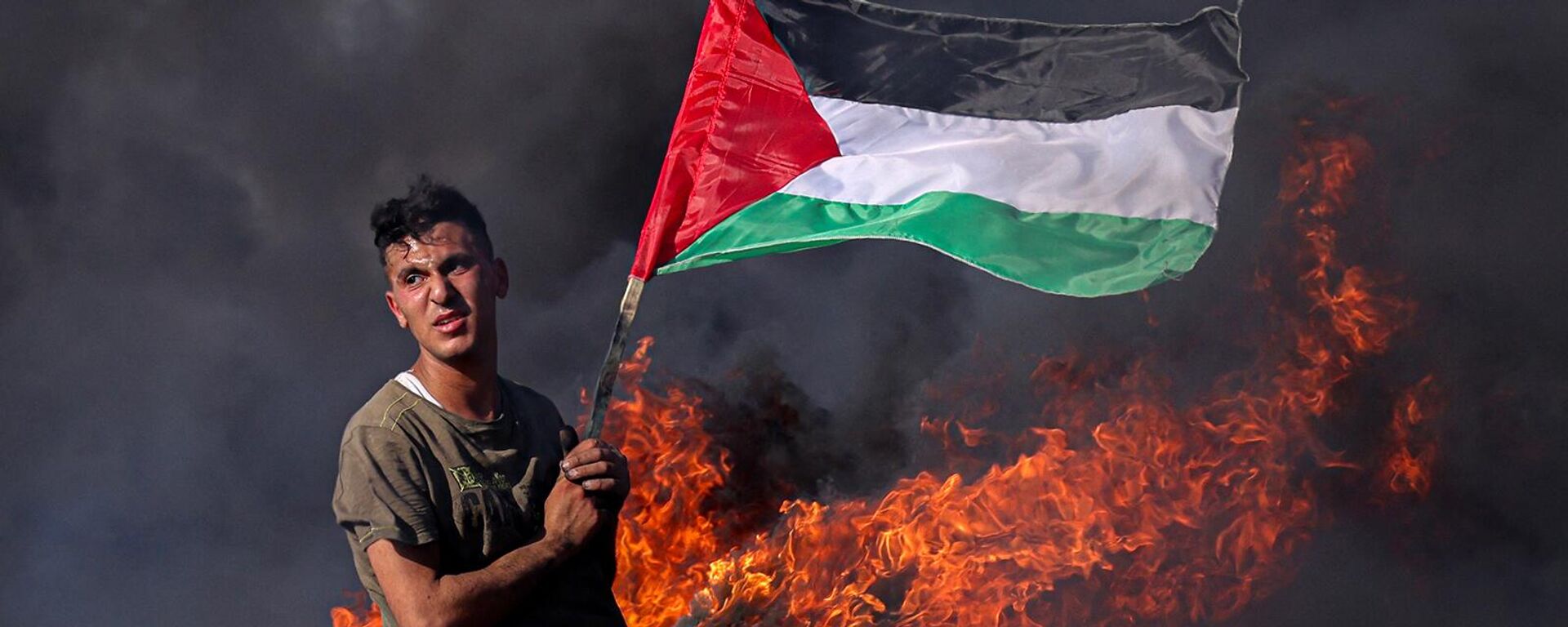 Палестинский юноша сжигает шины во время акции протеста у пограничного забора с Израилем (3 июля 2023). Газа  - Sputnik Армения, 1920, 30.10.2023