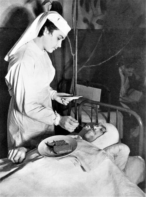 Медсестра Ленинградского Военно-морского госпиталя Анна Юшкевич кормит раненого краснофлотца - Sputnik Армения