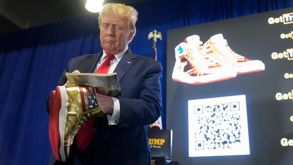 Кандидат в президенты США от Республиканской партии, бывший президент Дональд Трамп раздает автографы и держит в руках золотые кроссовки Trump Sneaker (17 февраля 2024). Филадельфия - Sputnik Армения