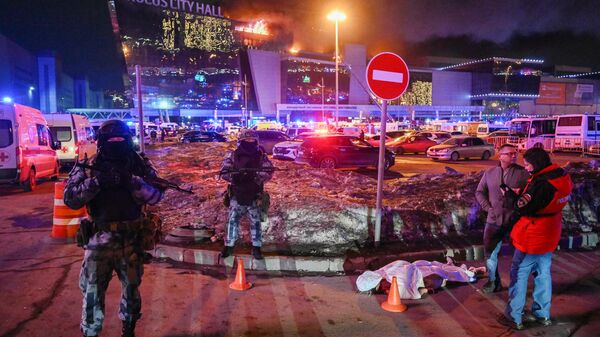 Сотрудники полиции рядом с телом погибшего у концертного зала Крокус Сити Холл, где произошла стрельба (22 марта 2024). Москва - Sputnik Армения