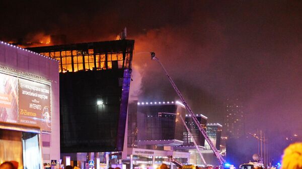 Пожарные тушат горящую крышу концертного зала Крокус Сити Холл, где произошла стрельба (22 марта 2024). Москва - Sputnik Армения