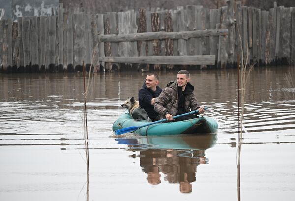 Мужчины плывут на надувной лодке по затопленной улице - Sputnik Армения