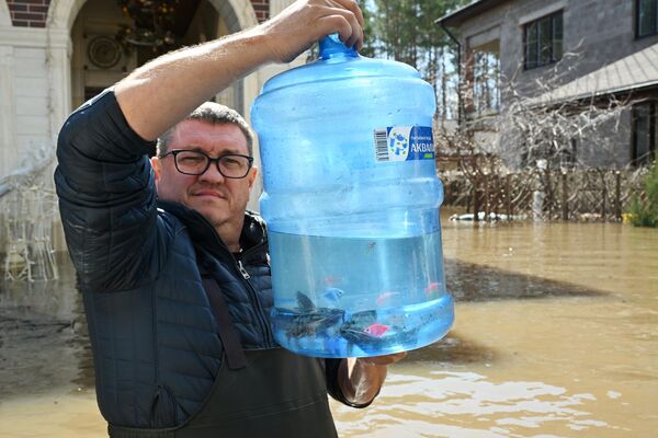 Местный житель эвакуируется из своего затопленного дома в селе Нежинка Оренбургского района - Sputnik Армения