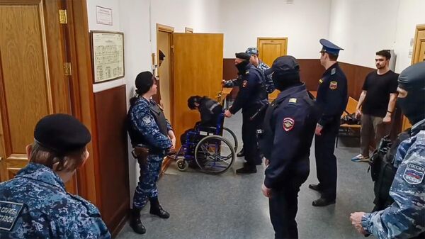 Сотрудники правоохранительных органов доставляют первого фигуранта дела о теракте в Крокусе Мухаммадсобира Файзова в зал суда (16 мая 2024). Москвa - Sputnik Армения