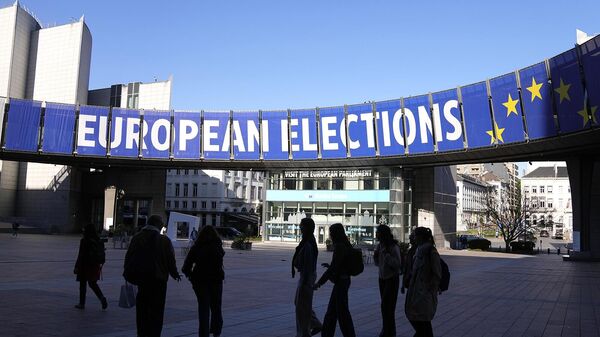 Группа стоит под предвыборным баннером возле Европейского парламента в Брюсселе (29 апреля 2024). Бельгия - Sputnik Армения
