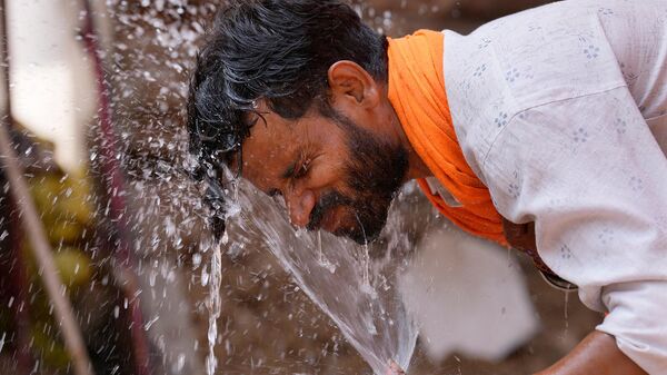 Мужчина под струей воды в жаркий летний день в Лакхнау (27 мая 2024). Индия - Sputnik Армения