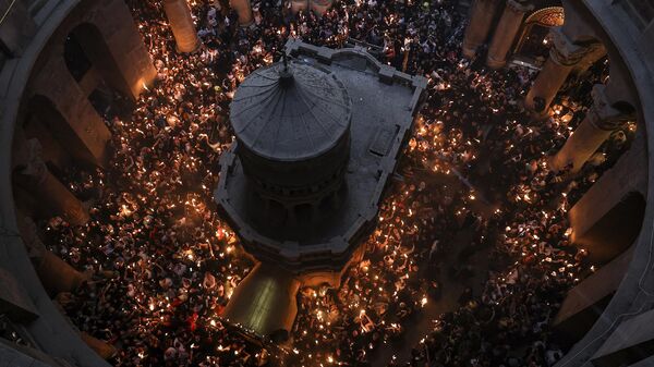 Православные христиане собираются с зажженными свечами вокруг Кувуклии, традиционно считающейся местом захоронения Иисуса Христа, во время церемонии Благодатного огня в храме Гроба Господня (15 апреля 2024). Иерусалим - Sputnik Армения