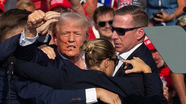 Кандидата в президенты США от Республиканской партии Дональда Трампа с окровавленным лицом, окруженного агентами секретной службы, уводят со сцены предвыборного мероприятия в Батлере (13 июля 2024). Пенсильвания - Sputnik Армения