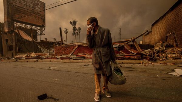 Мужчина проходит мимо охваченного огнем предприятия в Альтадене, Калифорни - Sputnik Армения