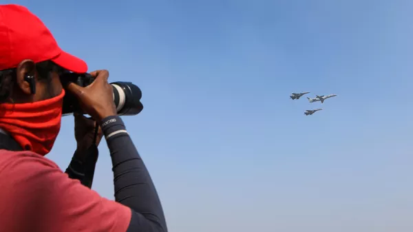 Фотограф снимает полет многоцелевых истребителей Су-30 и самолета дальнего радиолокационного обнаружения и управления ERJ-145I NETRA ВВС Индии на Aero India 2025  - Sputnik Армения